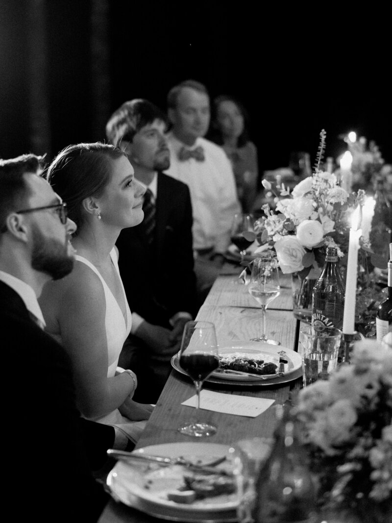 Black and white photo of bride and groom at their reception table
