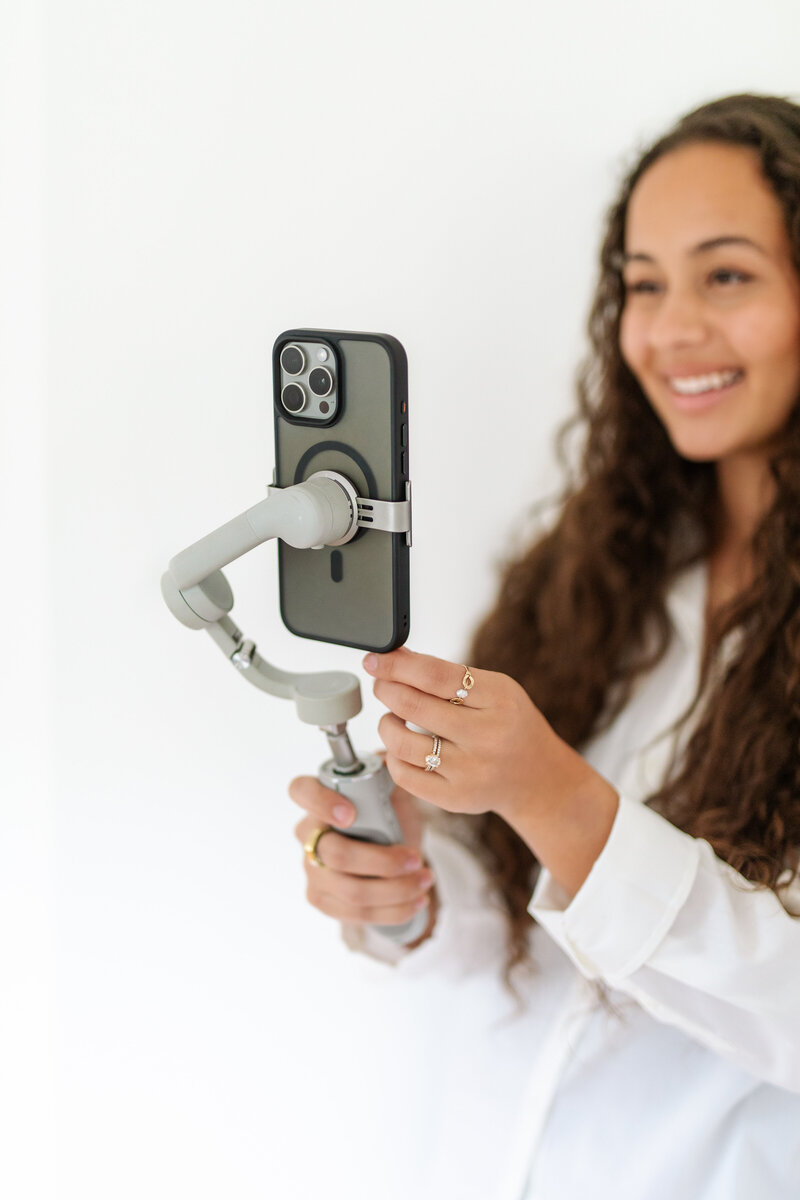 Lead wedding and event content creator, Makana Arvizu, holding up her gimble and phone to record content in Encinitas, California.