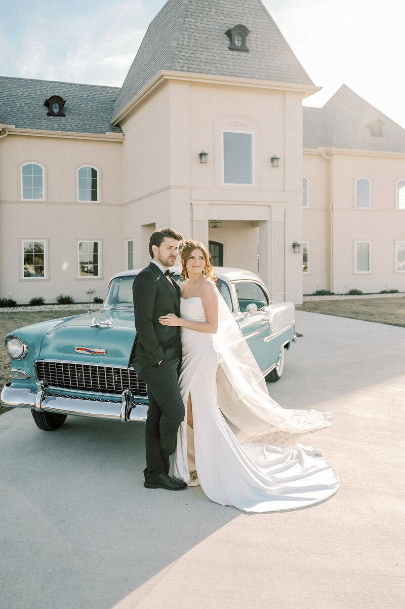 Dallas-Fort Worth Wedding Photographer | DFW Photographer Rae De Lain Weddings Light and Airy | Bride and groom stands in front of a dusty blue car at Chateau Joli