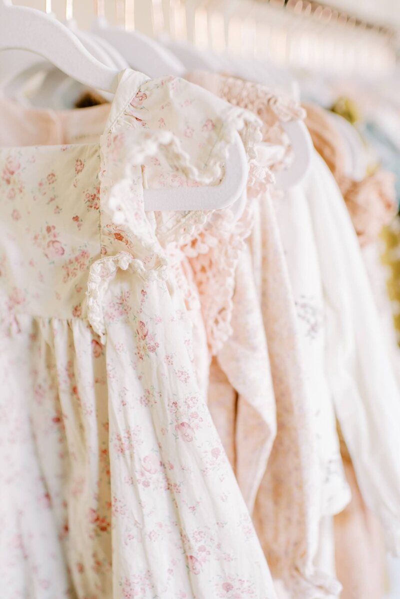 A pink floral Jamie Kay dress hangs in on a clothing rack