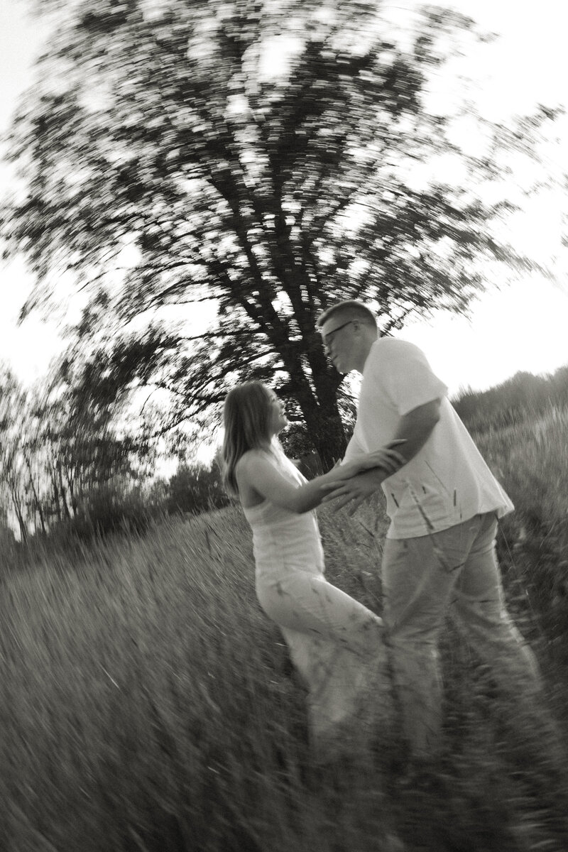 A newly engaged couple frolics in the prairie in Duluth, Minnesota during a summer engagement session.