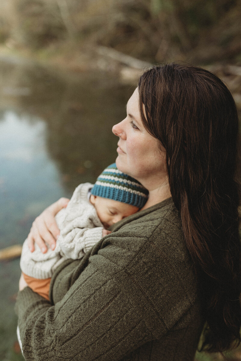 Newborn photographer cuddling a baby at a river
