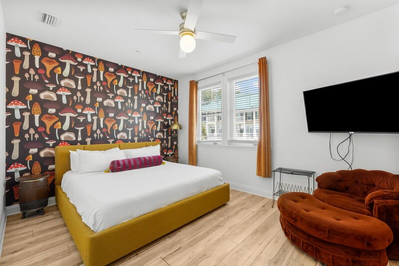 Whimsical king bedroom with mushroom-themed wallpaper, velvet seating, and 70s flair in Groovy Shack near Santa Rosa Beach and Destin.