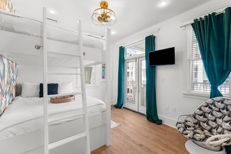 Bright and cheerful queen bunk room with private balcony access at The Florida House, a vibrant vacation rental near Panama City Beach and Grayton Beach.