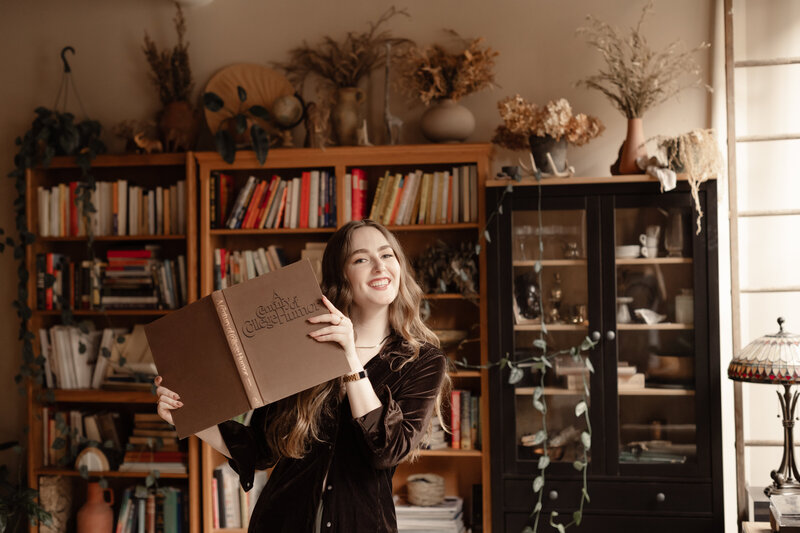 Copywriter smiling, peeking out behind a book in a moody room