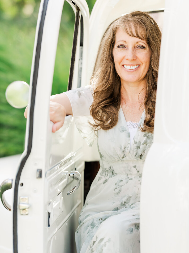 Jennifer Hall smiling and sitting in a white truck outdoors.