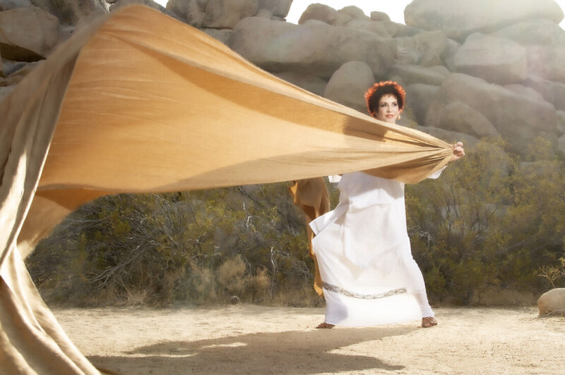 Music Artist Portrait Zephryn Conte standing beside rock mountain with long scarf blowing in wind
