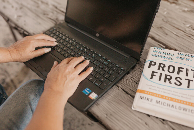 woman's hand on a laptop next to the profit first book