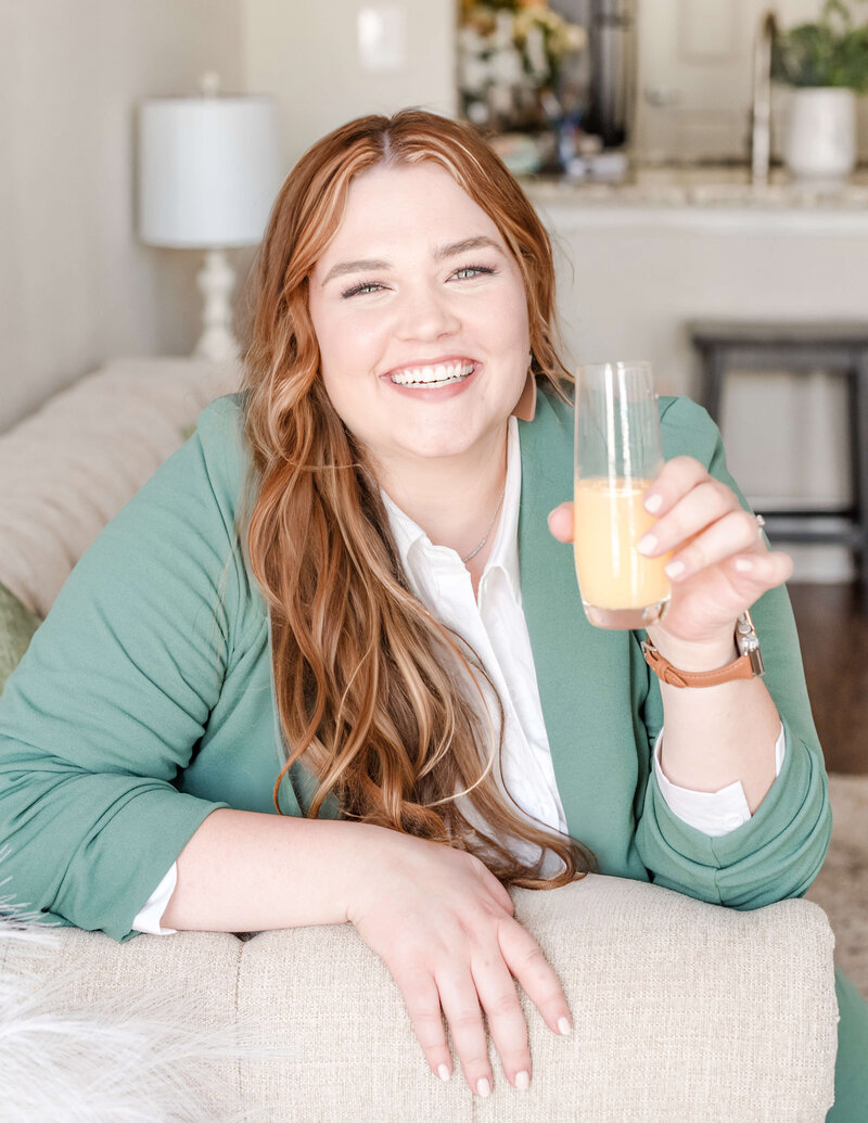 Elyse Stokes, owner of E Stokes Creations, cheersing with a mimosa, showing a friendly and inviting demeanor