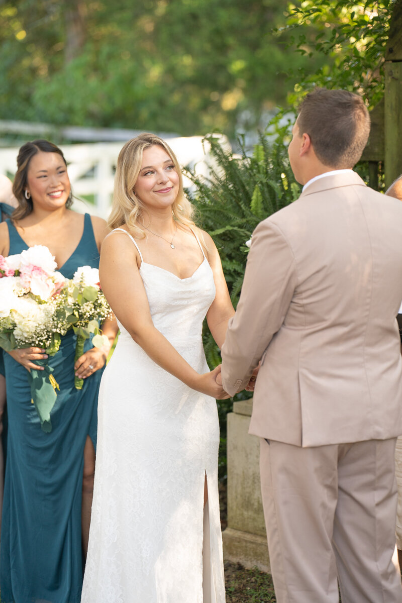 Bride smiling at her grooming while holding hands at the wedding alter  at Historic Tuckahoe in Richmond, Virginia.