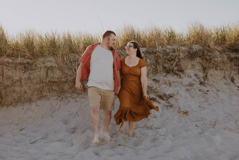 couple holding hands walking along the beach