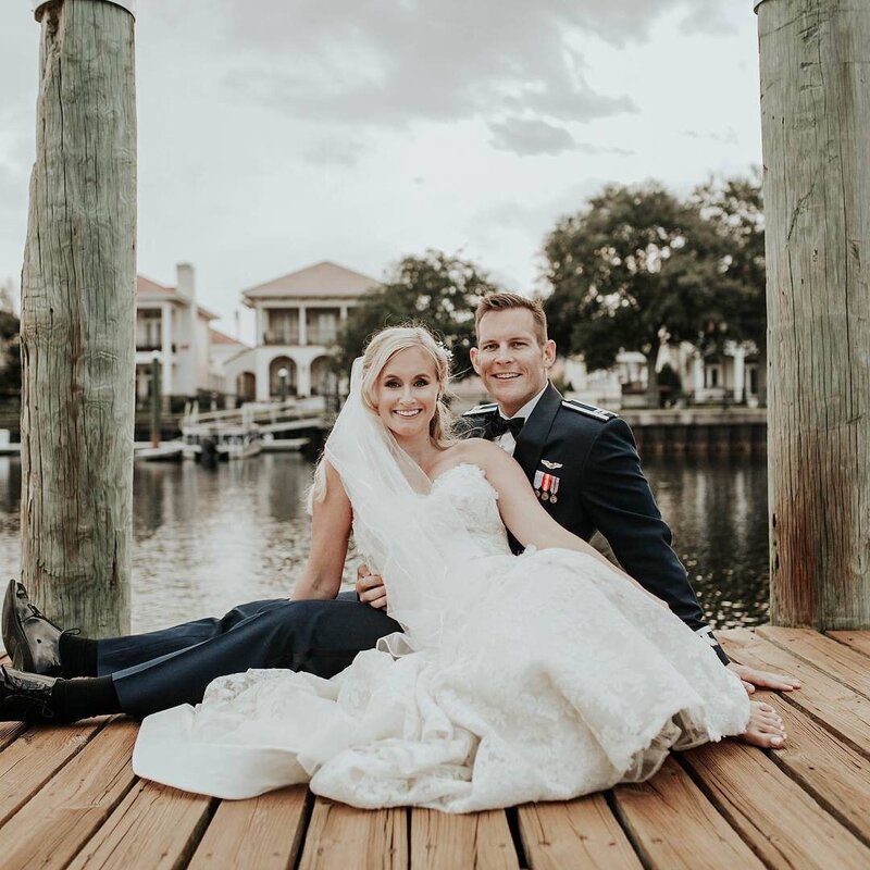 Military couple poses on dock at Palafox Wharf in Pensacola FL