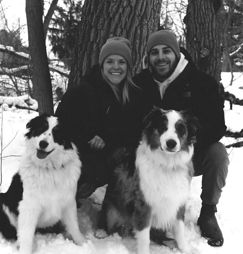A black and white family picture of a residential contractor and carpenter with his wife and two Australian Shepherds.