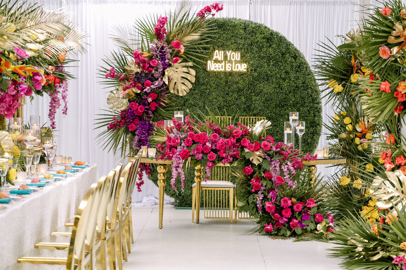 Floral, grass wall, neon sign, vibrant bride and groom table