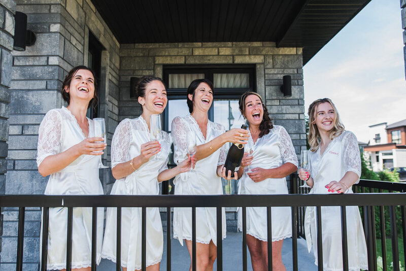 Le cortège de la mariée célèbre en faisant sauter le champagne devant leur maison, moment festif et spontané capturé dans une ambiance conviviale avant le mariage