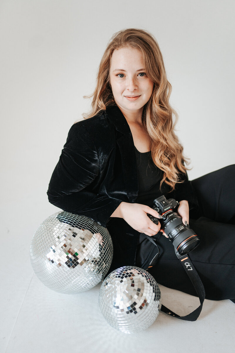Photographer Chloe Ray smiling and wearing a black button down shirt off the shoulder.