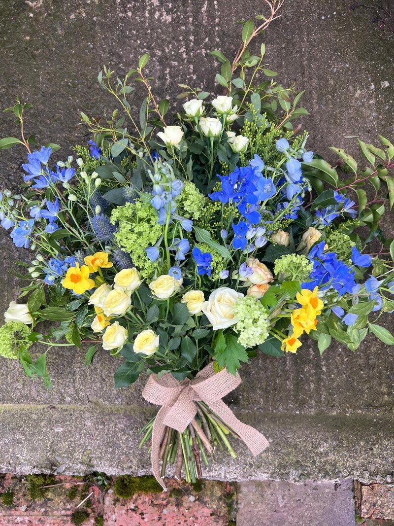 Hand-tied funeral sheaf of flowers in blue and yellow