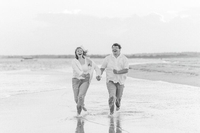Couple laughing and running on the beach.