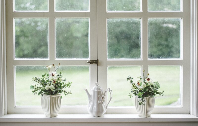 White planters and a teapot sitting in front of a window in an old home.