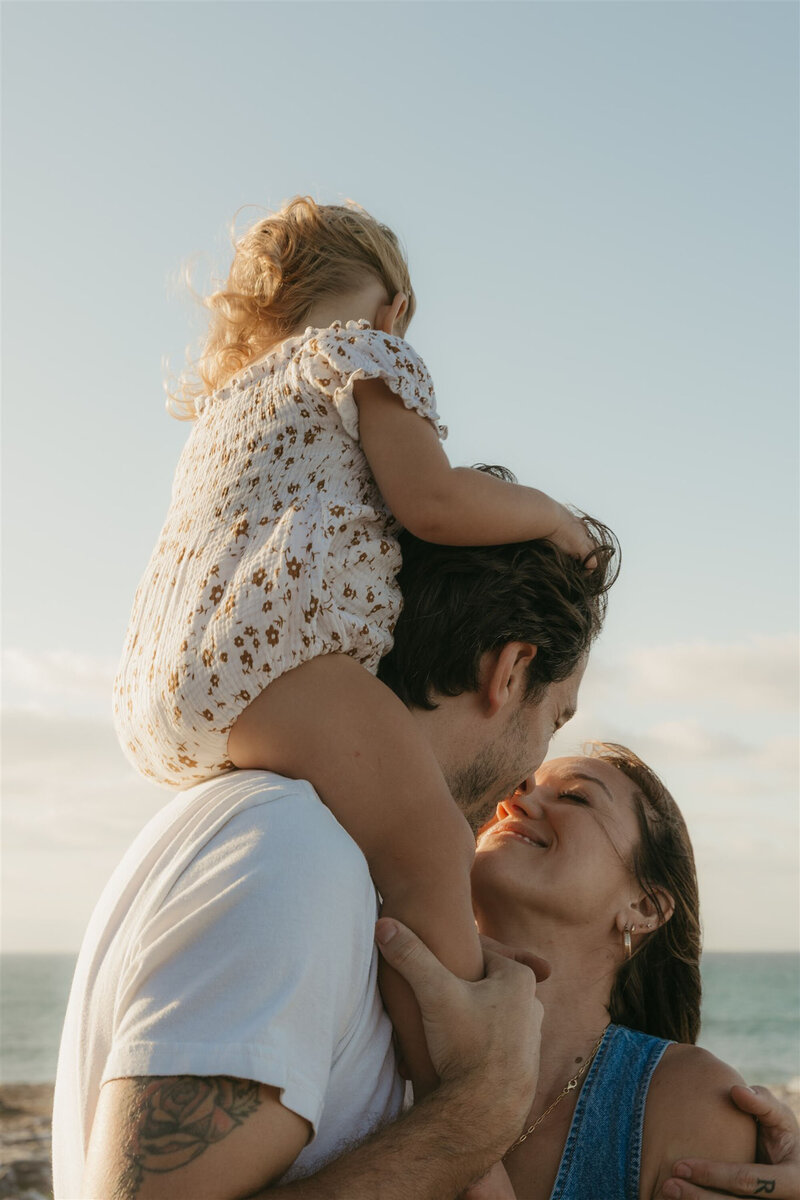Styled Maui family photography session on a cliffside, capturing candid laughter and connection in denim and neutral tones.”