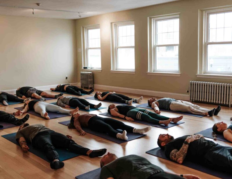 A group of participants lying on yoga mats during a guided breathwork session, wearing Ice Bath Boston & Breath branded shirts.