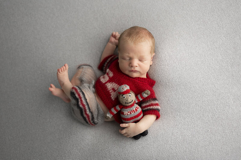 newborn in a sleeping pose on a wooden bed prop with blankets