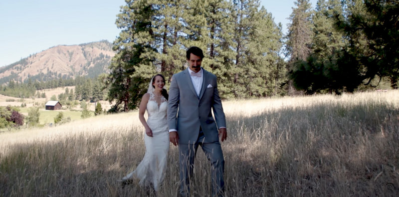 bride and groom holding hands while walking through a field