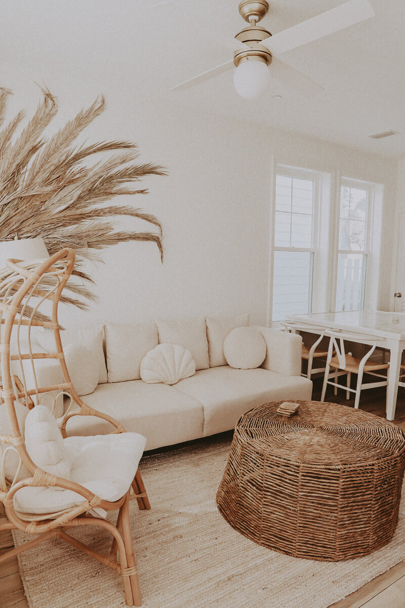 white sofa with shell throw pillows and a rattan coffee table