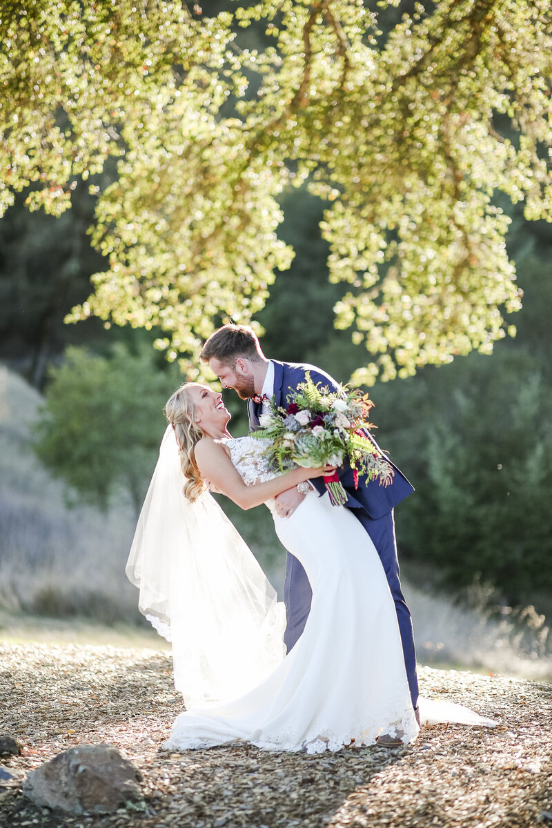 newlyweds dipping under the iconic oak tree at mountain house estate in cloverdale, ca