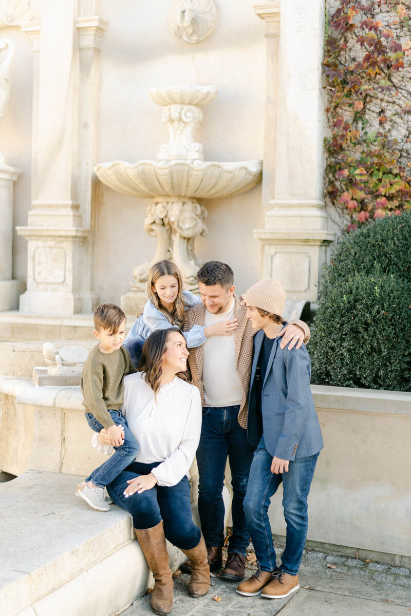 Family of five hangs out by a fountain at Longwood Gardens during a family photoragphy session with AnneMarie Hamant