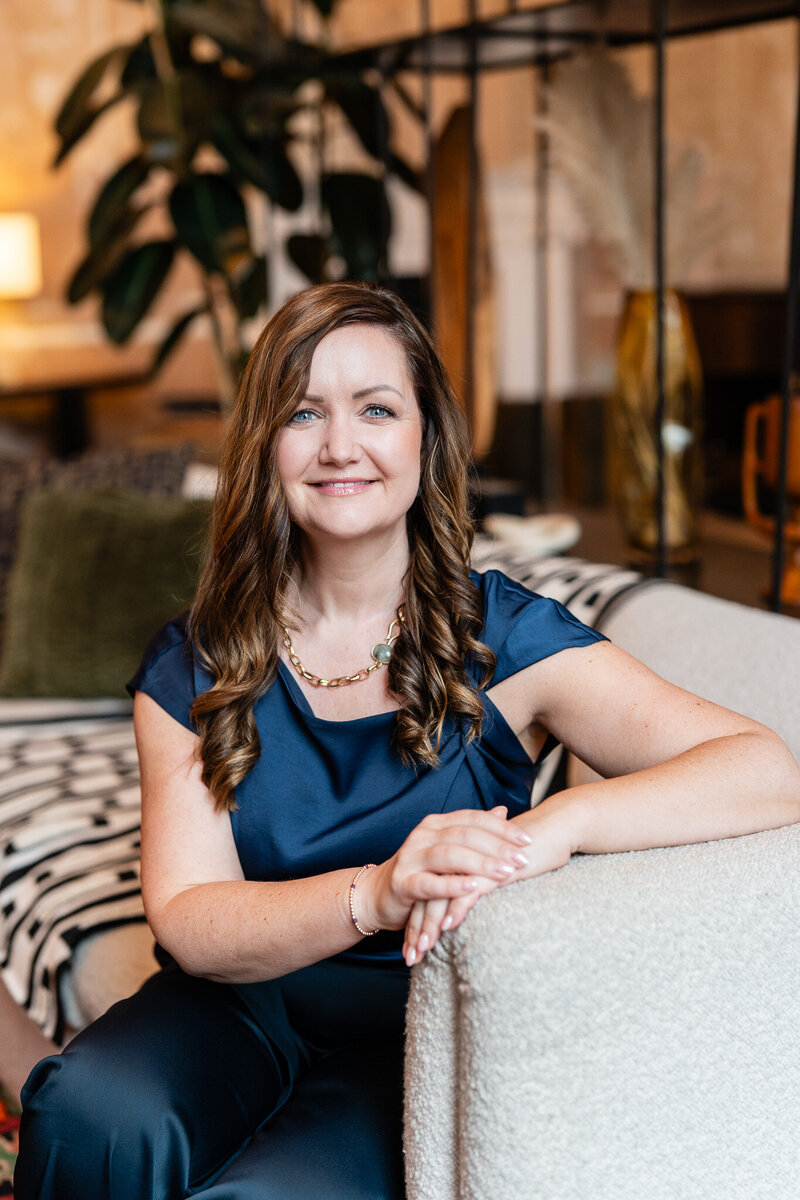 Bryony Williams in dark blue dress sitting on a sofa