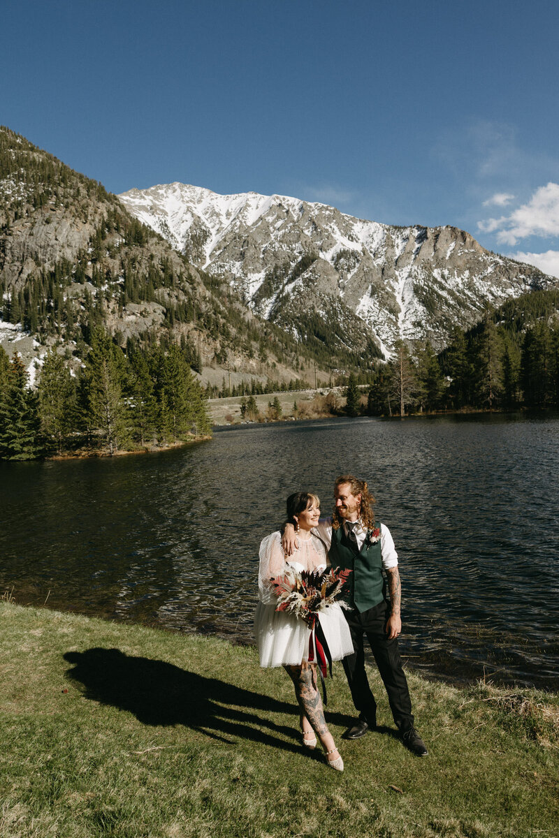 A wedding couple in Frisco Colorado with a huge mountain behind them while they smile. 