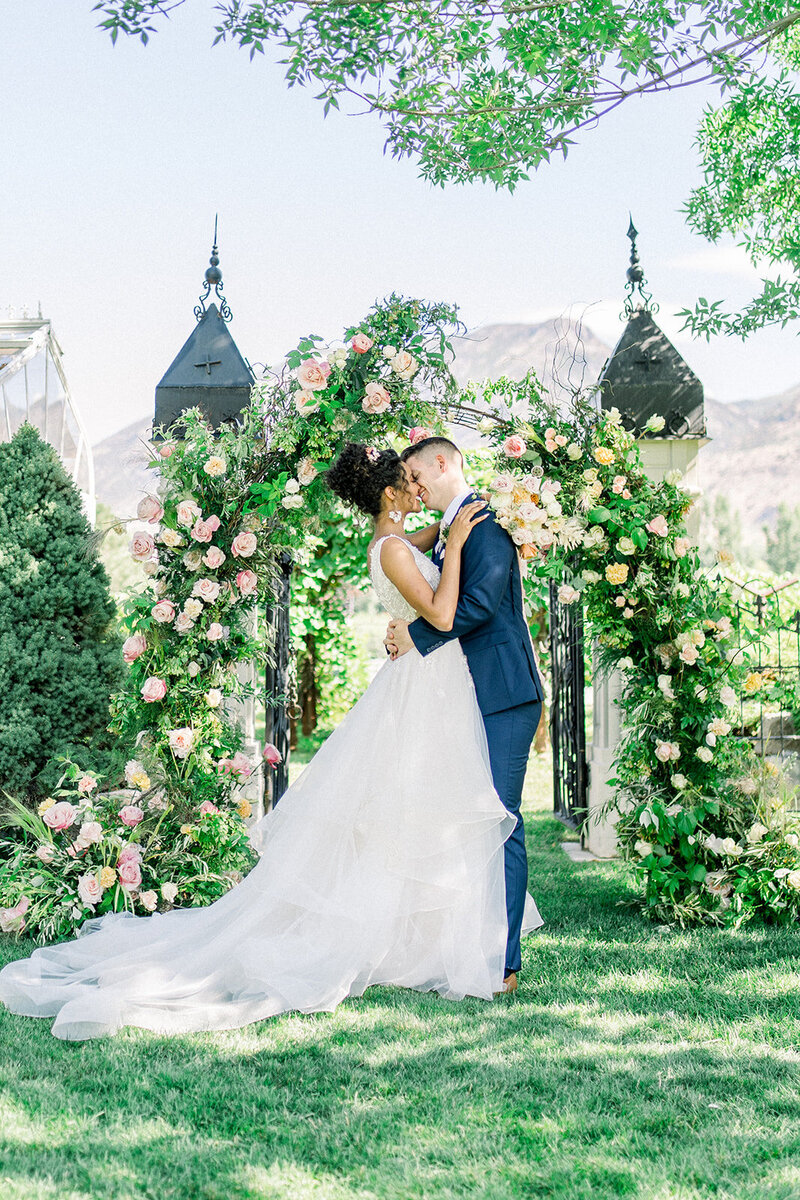 Tiffany Longeway Photography captures a breathtaking kiss between the bride and groom beneath a lush floral arch at Filoli Historic House and Garden in Woodside, California. The vibrant greenery and enchanting garden setting create a romantic and picturesque atmosphere, ideal for couples seeking a beautiful and historic venue for their wedding celebration.
