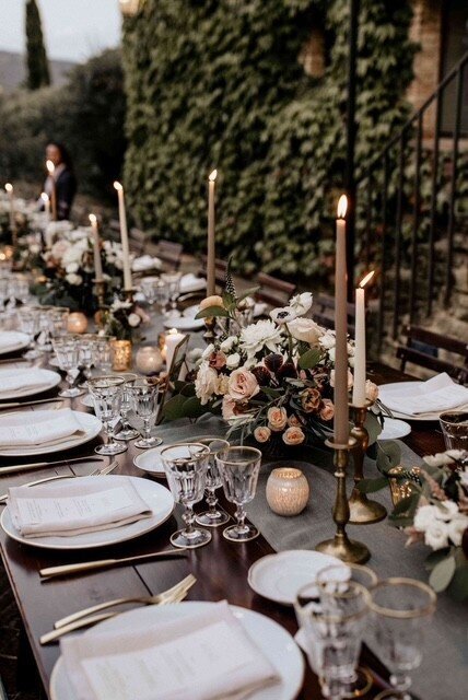 Outdoor tablescape featuring taupe candle sticks and tonal florals in peach, ivory, deep greens to match.