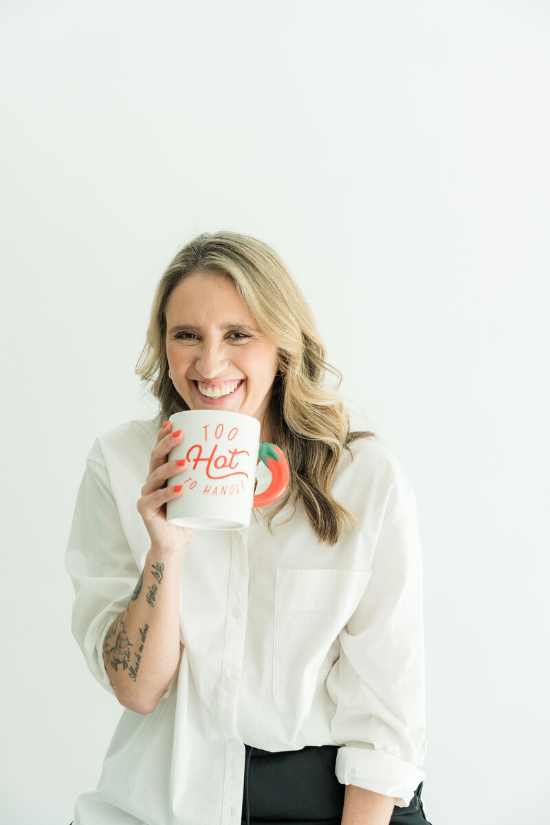 Confident brand designer dressed in branded colors, holding motivation in hand for women-led small businesses.