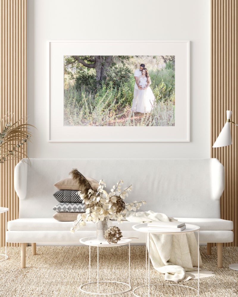 Beige white aesthetic modern living room with a portrait on the wall of a pregnant couple in a field.