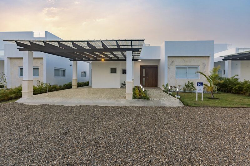 Exterior view of a luxury white villa with a carport at sunset, featured by Nova Lux DR Properties