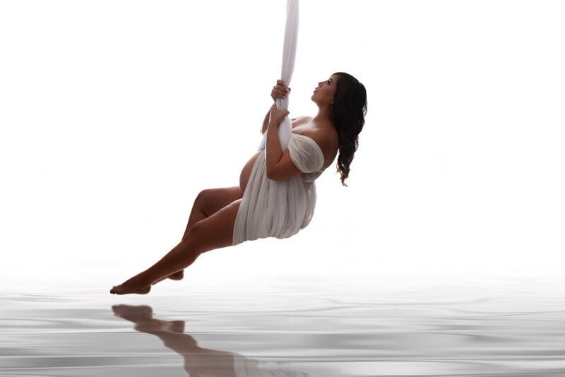 Atlanta, Georgia maternity photographer, Casey McMinn Photography,  photographing  34 week pregnant woman posed in sheer swing with water reflection below.