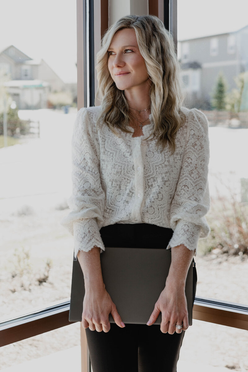 Kristin Tibbs looking out a window, symbolizing strategic planning and clarity for home sellers in Parker and Windsor, Colorado.