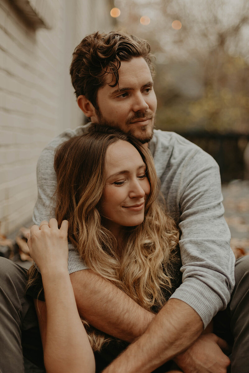man sitting with arms around fiance
