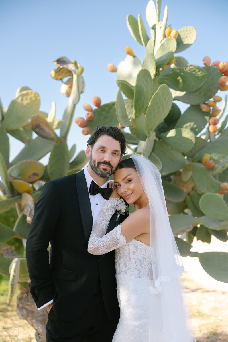 bride and groom standing in front of cactus
