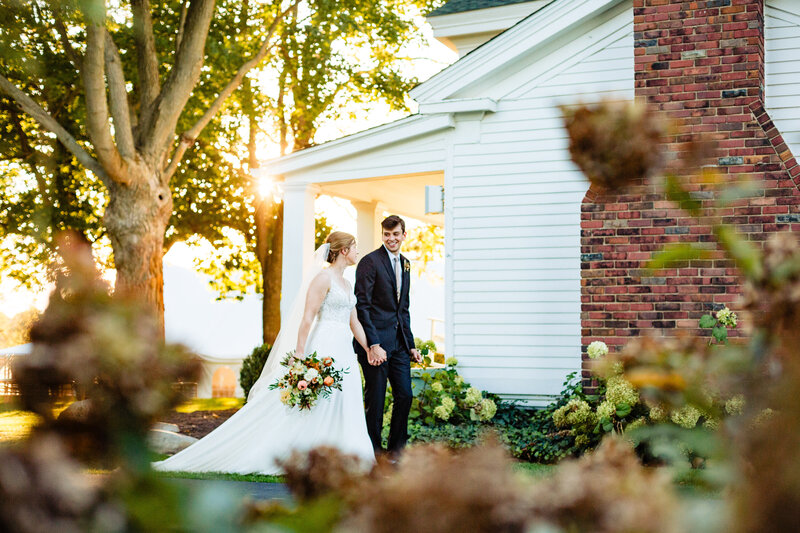 Golden hour at Cornman Farms in Ann Arbor Michigan while a wedding couple holds hands and walks away