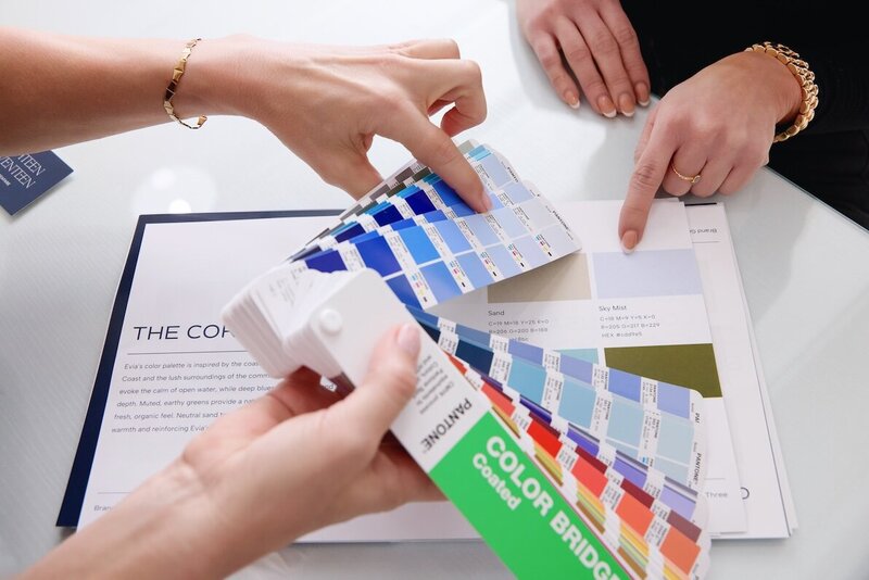 Hands reviewing color swatches and printed brand strategy documents at Jennifer Taormina & Co.—part of the creative development process for branding clients.