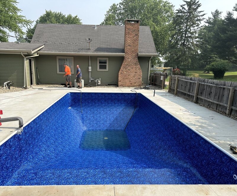 Finished concrete pool deck around a new blue liner and clean water in Goshen, IN