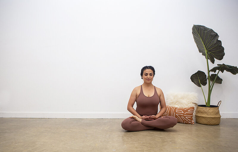 Pregnant yogi mom smiles in tree pose as her toddler daughter holds onto her leg smiling at Hotsource Yoga in Aptos