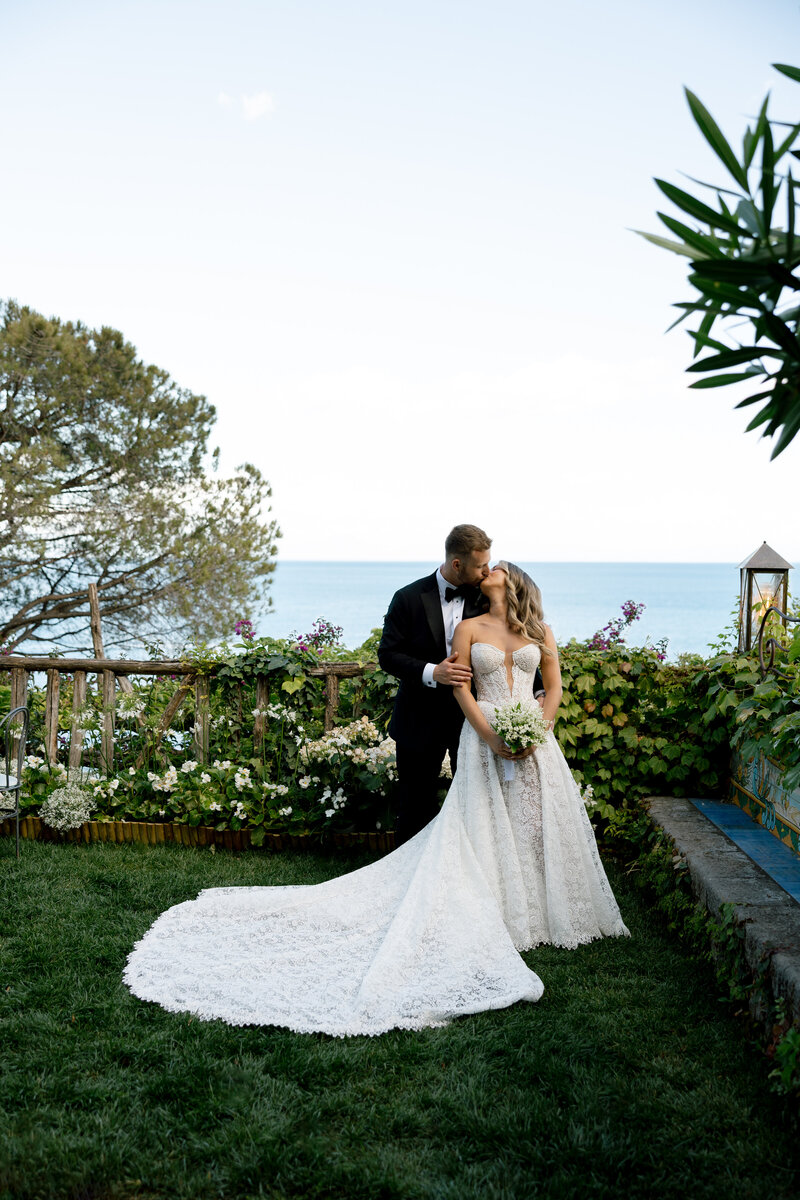 Bride smiling with the Amalfi Coast’s vibrant cliffs and ocean behind her.
