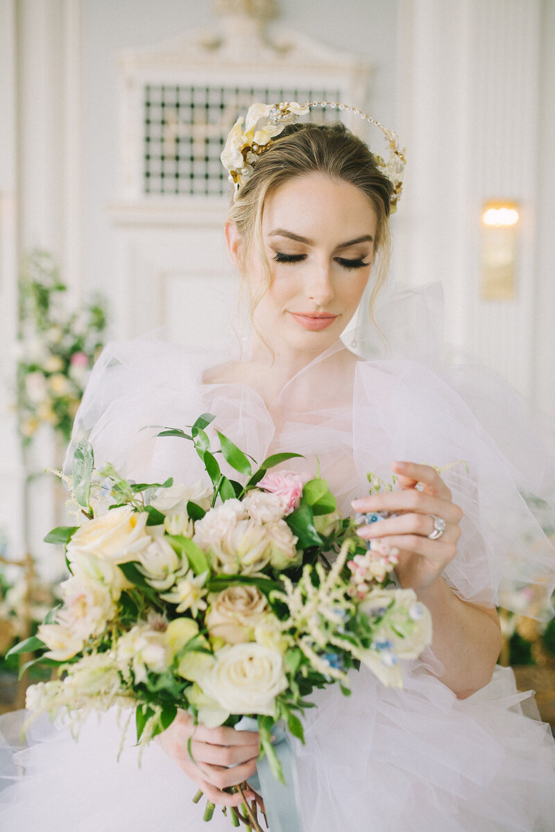 bride holding her bouquet  in a white gown and gold crown