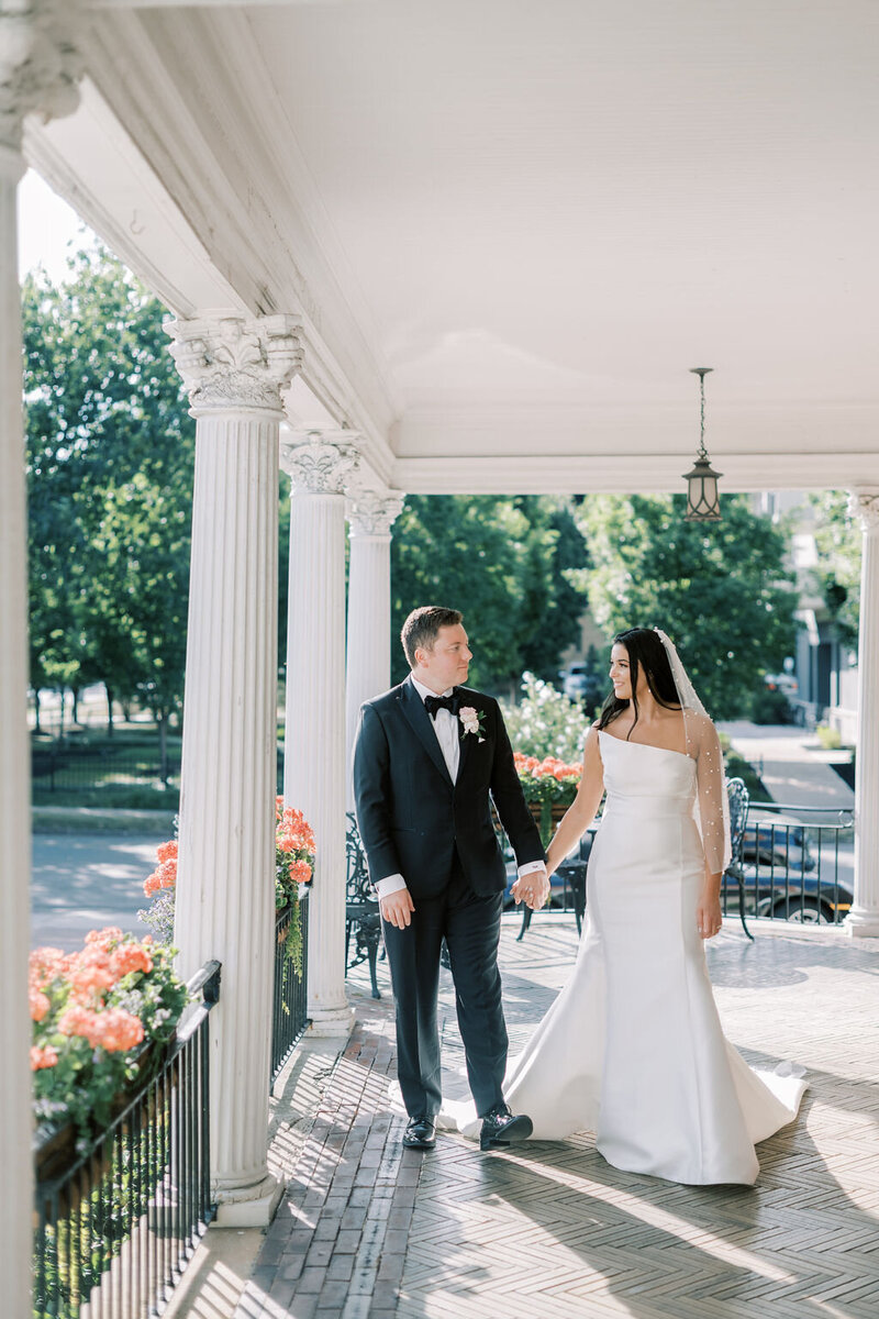 bride and groom walking on porch at the Strathallen in Rochester