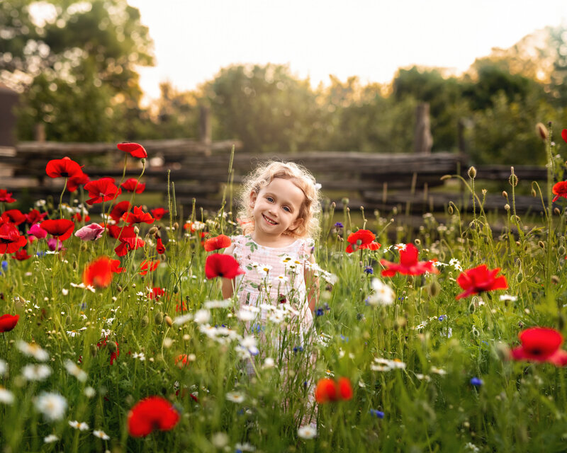 Full of color, joy, and sunshine, this outdoor milestone portrait captures a little girl’s delight in a blooming wildflower field.