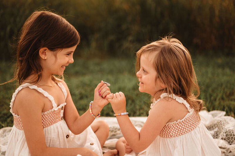 Two sisters sharing a pinky promise moment outdoors in Doylestown, Pennsylvania
